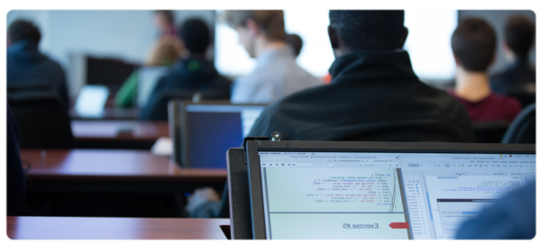 A Computer Science student sit at a flip top desk in the CS lab